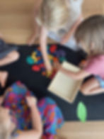 Three childre playing with LETme Toys cobblestones on a mat